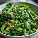 A nourishing Spring Green Bowl with blanched green beans and peas, topped with fresh herbs and seeds over warm grains for a wholesome meal.