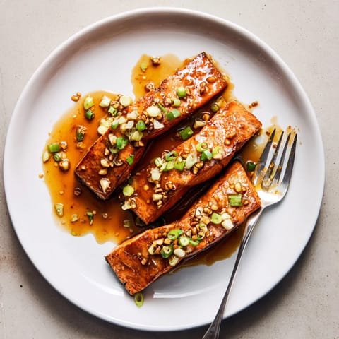 Perfectly cooked salmon fillets coated in a glossy honey garlic sauce, garnished with green onions and sesame seeds.
