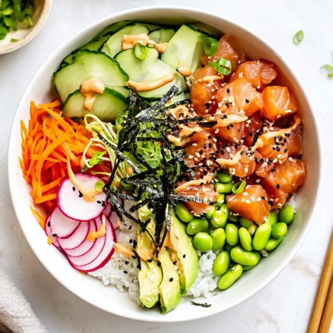 Colorful Hawaiian-inspired poke bowl featuring diced tuna, cucumber, edamame, and carrots, topped with sesame seeds and nori strips.
