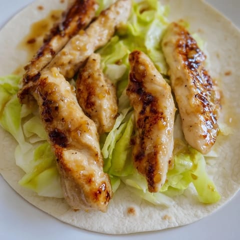 Freshly rolled honey mustard chicken wrap cut in half, revealing tender cooked chicken, shredded lettuce, and a creamy honey-mustard dressing inside.
