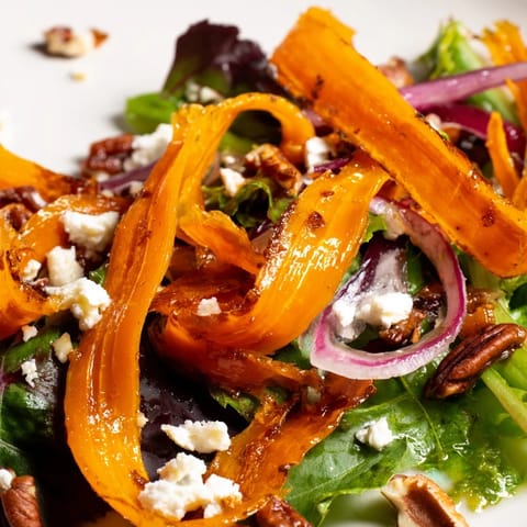 The finished Roasted Carrot Ribbon Salad features tender, caramelized carrots on a bed of mixed greens, drizzled with honey-mustard vinaigrette.