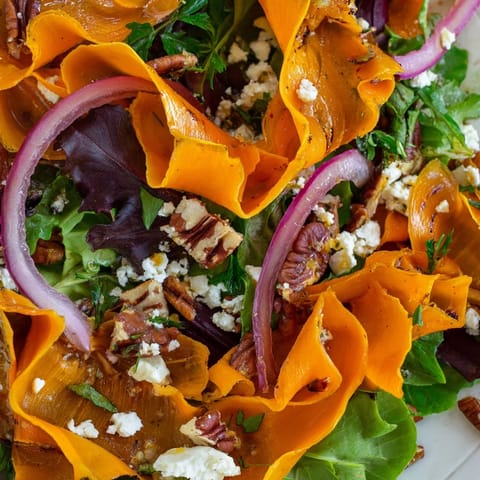Vibrant orange carrot ribbons roasted to perfection are tossed with fresh arugula, red onion, and crumbled feta for a bright, tangy salad.