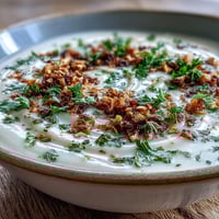 Creamy roasted celeriac soup with hazelnut crumble served hot in a rustic bowl.