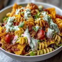 Taco Pasta Salad with Doritos and Avocado Ranch in a colorful bowl with crunchy tortilla chips on top.